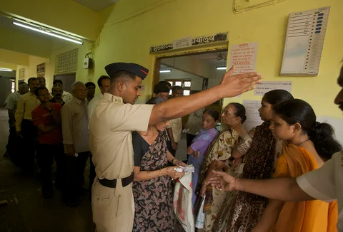 A policeman guides a voter at a polling station (Photographer: Adeel Halim/Bloomberg News)