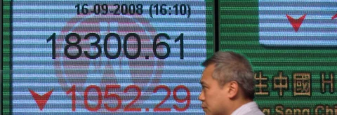 A man walks in front of an electronic board showing the closing figure of the Hang Seng Index in Hong Kong, on Sept. 16, 2008. (Photographer: Jerome Favre/Bloomberg News)
