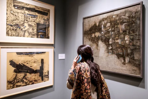 A visitor talks on the phone as she looks at paintings during the preview show of Christie’s South Asian Art auction in Mumbai. (Photographer: Dhiraj Singh/Bloomberg)