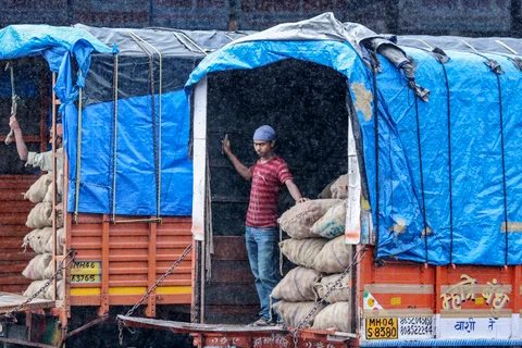 A worker stands beside sacks of onions loaded on a truck in the rain at the Vashi Agricultural Produce Market Committee (APMC) wholesale market in Mumbai. (Photographer: Dhiraj Singh/Bloomberg)