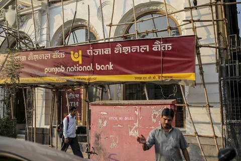 Pedestrians walk past a Punjab National Bank branch in Mumbai. (Photographer: Dhiraj Singh/Bloomberg)