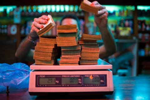 A manager weighs banknotes on a scale. (Photographer: Manaure Quintero/Bloomberg)