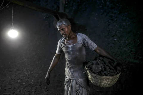 A worker carries a basket of charcoal at a coal wholesale market in Mumbai. (Photographer: Dhiraj Singh/Bloomberg)
