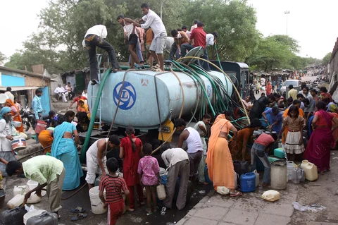 Residents of a poor area fill containers from a government water supply tank, in New Delhi, India. (Photographer: Pankaj Nangia/Bloomberg)
