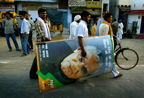 A BJP supporter carries a picture of then Prime Minister Atal Bihari Vajpayee after an election rally in Aligarh, on April 29, 2004. (Photographer: Amit Bhargava/Bloomberg News)