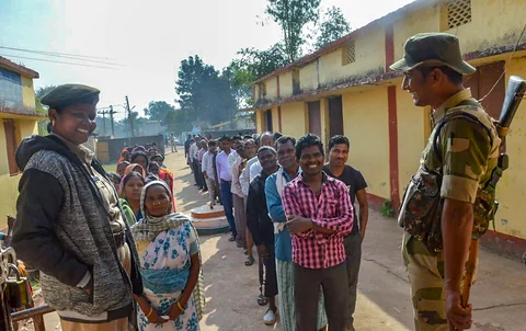 Security personnel stand guard as people wait in queues to cast their votes in Chhattisgarh, on Nov. 12, 2018. (Photograph: PTI)