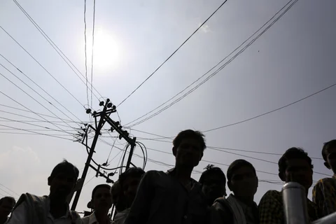 Residents of Dhadgaon village in Maharashtra under an electricity transmission pole and cables. (Photographer: Dhiraj Singh/Bloomberg)