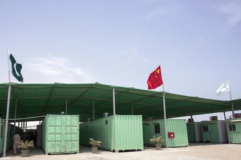 A Pakistani and Chinese national flag fly next to containers at a workers camp, operated by China Overseas Ports Holding Co., in Gwadar, Balochistan, Pakistan. (Photographer: Asim Hafeez/Bloomberg)