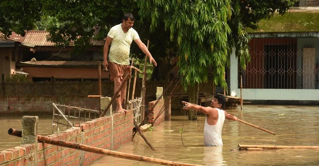People prepare a route from bamboo to move to a safer place from their submerged house following heavy monsoon rain at Panikhaiti in Kamrup district of Assam