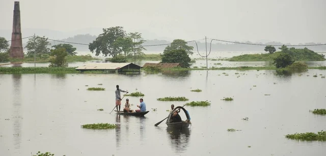People move to a safer place from a flood-affected area on a boat in the Kamrup District of Assam