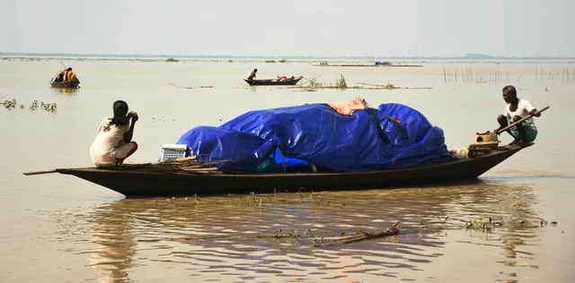 People move to a safer place on a boat from a flood-affected area at Panikhaiti in Kamrup district of Assam