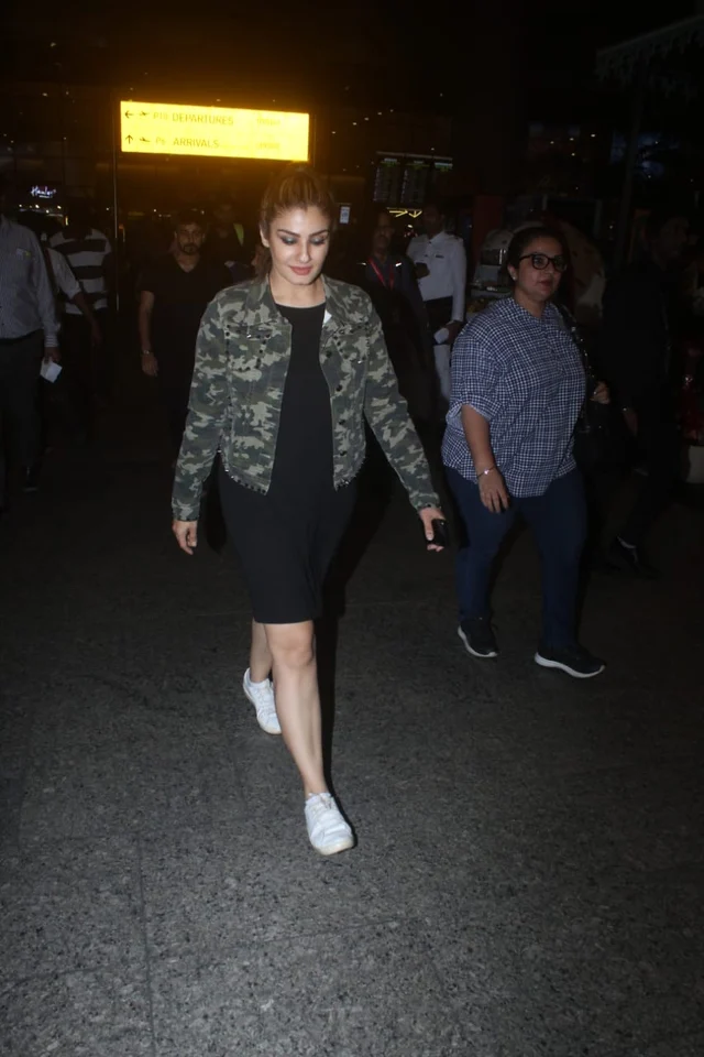 Raveena Tondon spotted by shutterbugs at airport in a stunning black dress a camouflage jacket.