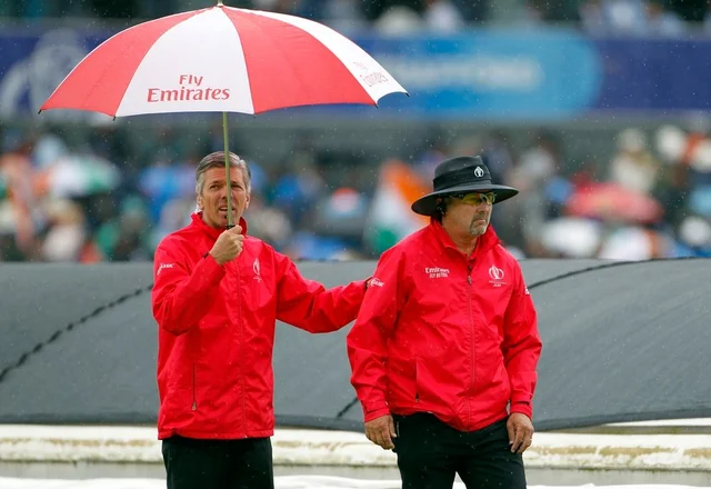 Umpires leave the ground as the rain interrupts the Semi-Final match between India and New Zealand at Old Trafford in Manchester on Tuesday.