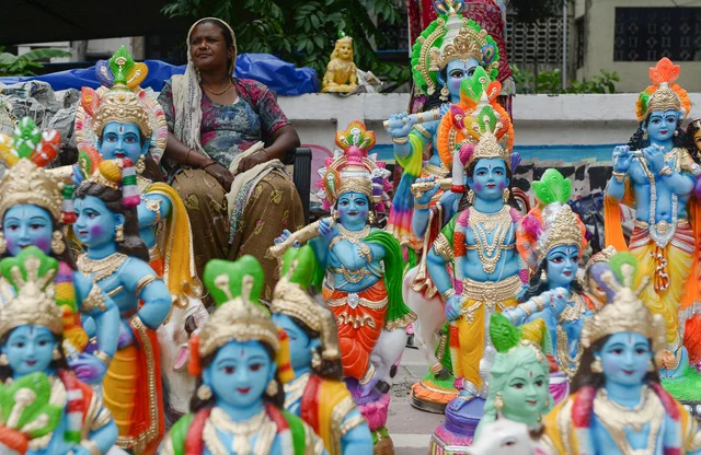 A vendor sits as she sells models of the Hindu deity Krishna on display at a roadside ahead of the 'Janmashtami' festival in Chennai