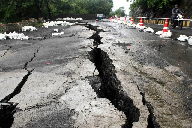 A man rides past a cracked portion of the national hihgway in Kasara, Maharashtra, following heavy rain.