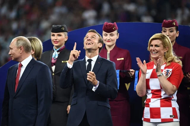 TOPSHOT – French President Emmanuel Macron (C) gestures between Croatian President Kolinda Grabar-Kitarovic (R) and Russian President Vladimir Putin during the trophy ceremony at the end of the Russia 2018 World Cup final football match between France and Croatia at the Luzhniki Stadium in Moscow on July 15, 2018.