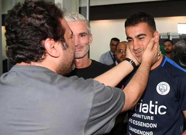 A supporter receives footballer Hakeem al-Araibi (R) upon his arrival at the airport in Melbourne with former Australian football captain Craig Foster (C) on February 12, 2019, following Araibi’s departure from Thailand after Bangkok dropped extradition proceedings against him at Bahrain’s request. Photo by WILLIAM WEST / AFP