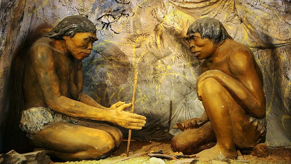Diorama of earliest human species (Homo <i>erectus</i>) sheltered in a cave with rock art