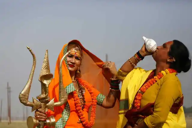 20 नवंबर, मंगलवार को इलाहाबाद में कुंभ मेले से पहले भारतीय ट्रांसजेंडर संतों की गुरू भवानी मां (बाएं) एक त्रिशूल धारण करते हुए तो वहीं दूसरा ट्रांसजेंडर शंख बजाते हुए. 