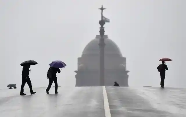 22 जनवरी की सर्द सुबह में बारिश के बीच रायसीना हिल्स पर चलते हुए लोग.