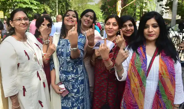 नोएडा में वोट डालने के बाद पोलिंग बूथ से निकलती महिलाएं