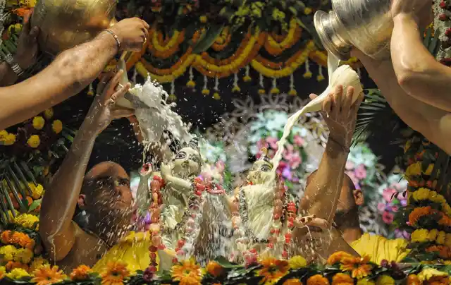 कोलकाता के मायापुर में इस्कॉन मंदिर में राधाष्टमी पर राधा कृष्ण की मूर्ति पर दूध चढ़ाते हुए भक्त (6 सितंबर 2019)