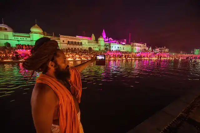 दीपोत्सव समारोह में सरयू नदी के तट पर सेल्फी लेता एक साधु