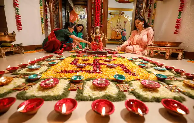 दिवाली से पहले रंगीन चावल, सूखे आटे, रंगीन रेत और फूलों की पंखुड़ियों से रंगोली बनाती महिलाएं