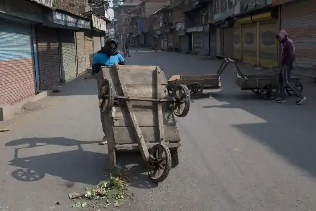 श्रीनगर में कश्मीरी पुरुष सड़क रोकने के लिए रेहड़ियों को सड़क पर जमा करते हुए (29 अक्टूबर)