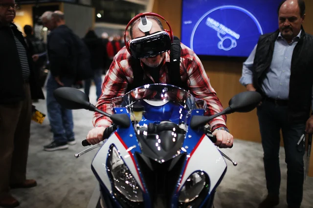 A man uses a VR head-set while sitting on a motorcycle. (Photo: Spencer Platt/Getty Images)