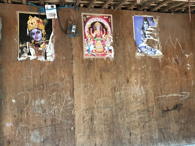 Pictures of gods and goddesses stuck on the wall of a house.