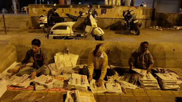 Newspaper hawkers prepare for the morning delivery. (Photo: AP)