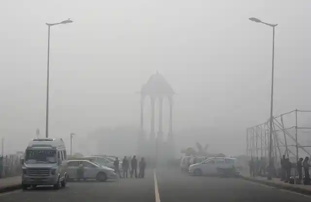 Vendors selling drinks stand beside vehicles near the India Gate war memorial on a smoggy day in New Delhi. (Photo: Reuters)