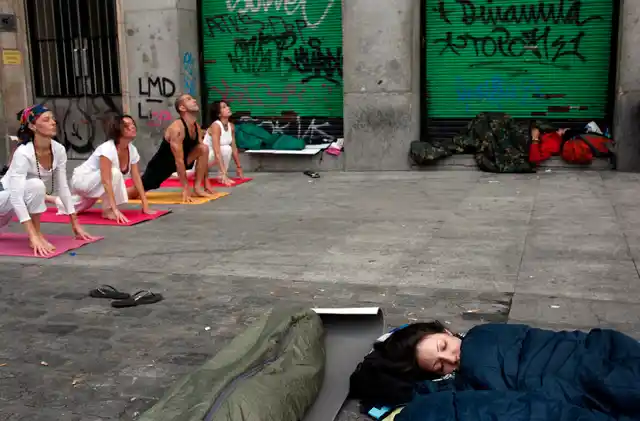 Demonstrators sleep as people practice yoga at Madrid’s Puerta del Sol, four days after Spanish regional and local elections. (Photo: Reuters)