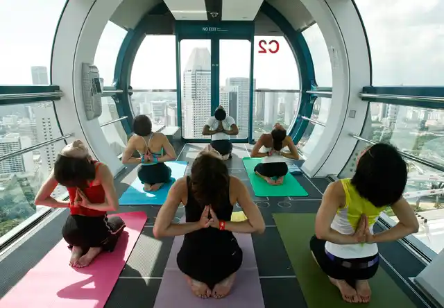 People take part in a yoga class on a capsule of the Singapore Flyer observation wheel in Singapore, better known as ‘Yoga in the Sky’. (Photo: Reuters)