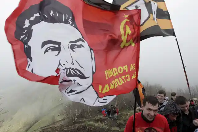 People climb up Mount Beshtau while holding a flag with an image of Soviet leader Joseph Stalin in Russia on the 70th anniversary of their victory over Nazi Germany in World War II. (Photo: Reuters)