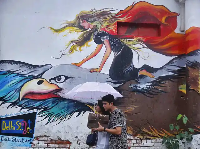 A couple walk in front of a graffiti painted wall during a rain shower in Delhi (Photo: Reuters) (Picture for representation purposes only)