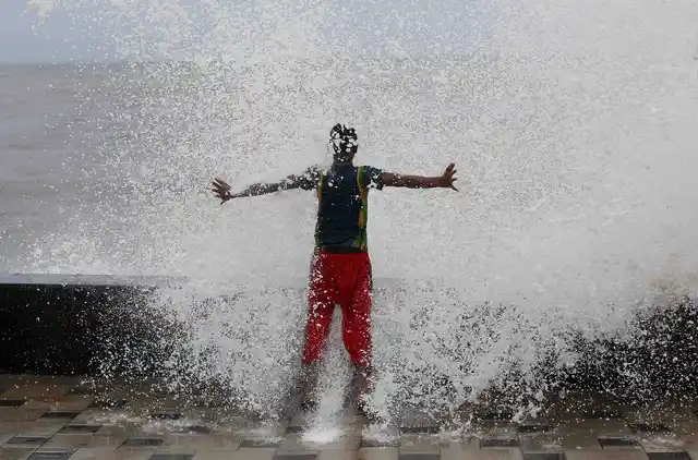 A boy stands near a wall as a wave comes crashing in Mumbai (Photo: Reuters) (Picture for representation purposes only)