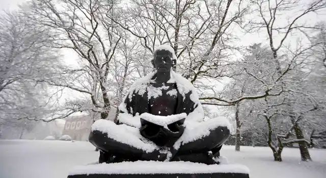 Snow falls on a statue of Mahatma Gandhi on a winter morning in the Ariana Parc outside the European headquarters of the United Nations in Geneva (Photo: Reuters)