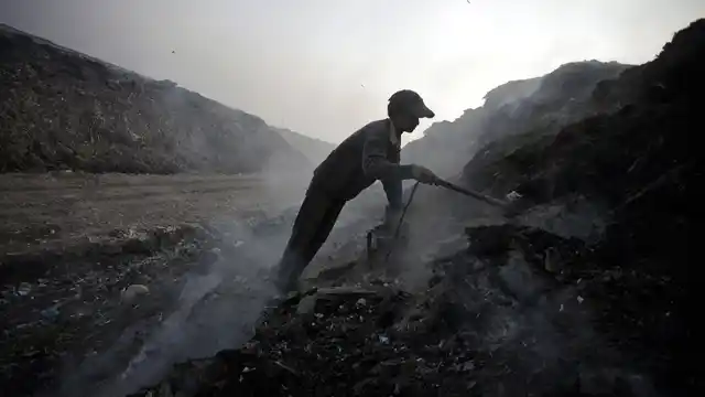 A scavenger sifts through ashes of waste for scrap metals in a garbage dump on the outskirts of New Delhi. (File photo: Reuters)