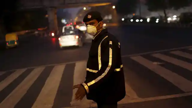 A traffic policeman wears a mask to protect himself from dust and air pollution as he signals to drivers in New Delhi, December 23, 2015. (Photo: Reuters)