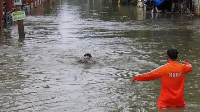 An NDRF official (right) arrives to rescue a boy who fell while wading through flood waters in Chennai. (Photo: AP)