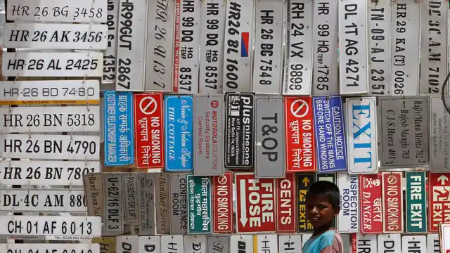 A boy stands in front of displayed car number plates and other signs at an automobile market in Gurgaon on the outskirts of New Delhi. (File photo: Reuters)