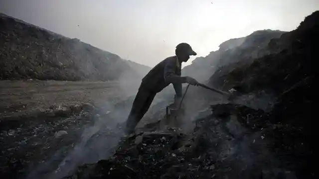 A scavenger sifts through ashes of waste for scrap metal in a garbage dump on the outskirts of New Delhi. (File photo: Reuters)