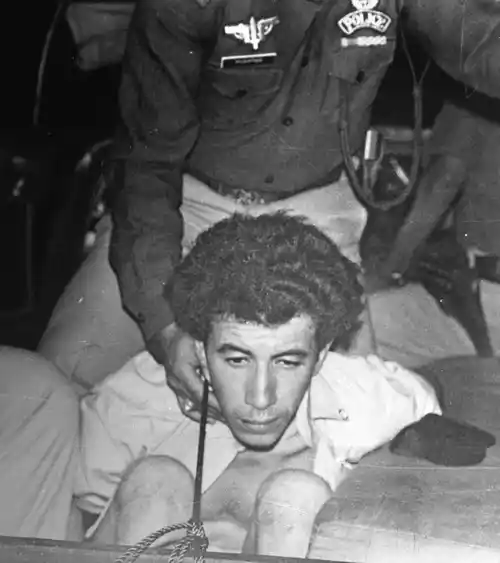 A man, said to be one of the four Pan Am hijackers, is cuffed as he is brought to a police car, at Karachi airport, Pakistan, Friday, Septemper 5, 1986. (Photo: AP)