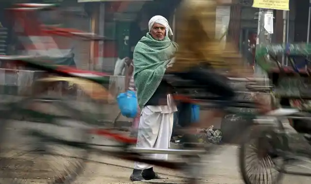 A man looks on as a rickshaw passes by at a busy market in the old quarters of Delhi, 29 February 2016. (Photo: Reuters/Cathal McNaughton)