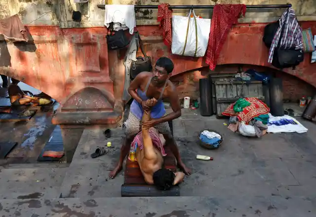 A masseur gives a massage to a customer on the banks of the river Ganges in Kolkata, 3 March 2016. (Photo: Reuters/Rupak De Chowdhuri)