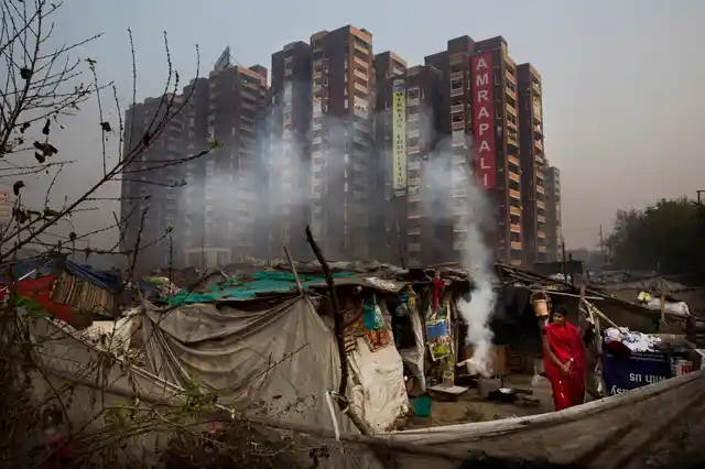 A woman uses a traditional mud stove in the area in front of her hut in a slum in the outskirts of New Delhi. (Photo: AP Photo/Bernat Armangue)