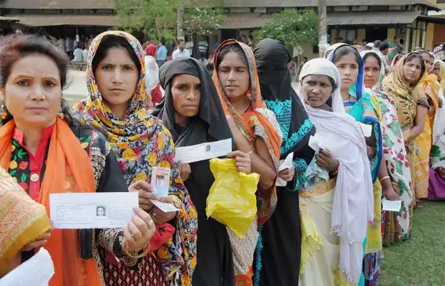 Voters stand in queue to cast votes at a polling booth during the second phase of state assembly elections in Baska, Assam on Monday. (Photo: PTI)