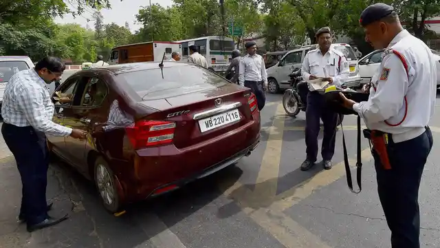 Traffic police men slap a challan to a commuter for riding with number plate ending with an even digit in New Delhi on the first day of the second phase of odd-even scheme. (Photo: PTI)